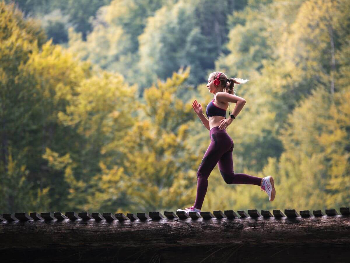 Žena bežiaca po drevenom moste v prírode.