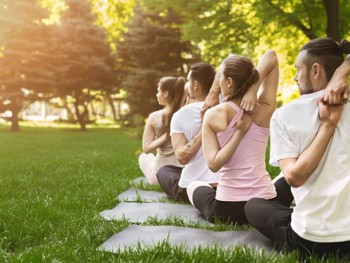 Ľudia praktizujúci jogu na karimatkách v prírode.