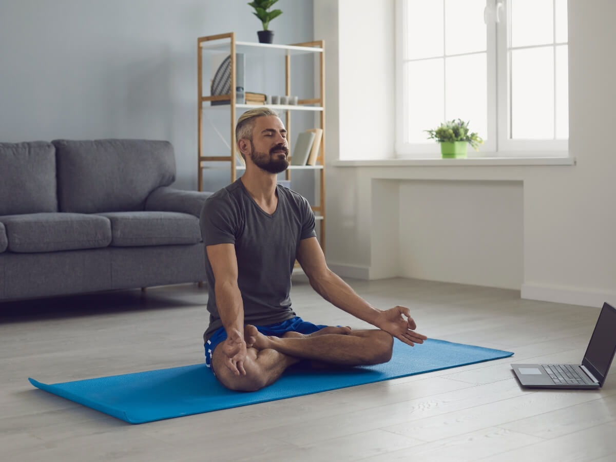 Muž meditujúci doma na karimatke.