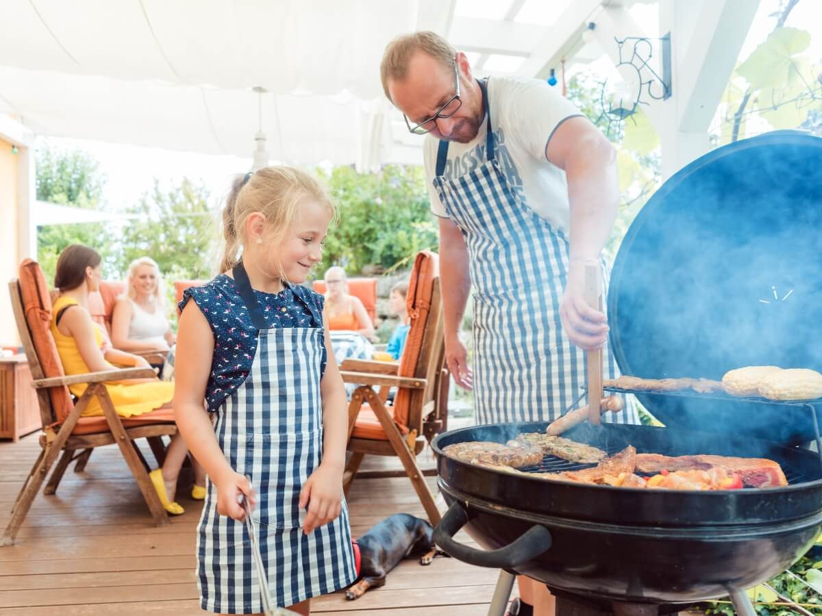Otec s dcérou a s rodinou na spoločnej grilovačke na terase.