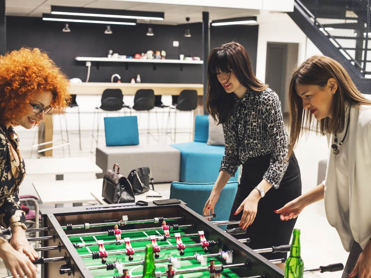 Ženy sa zabávajú v práci pri stolnom futbale.